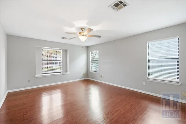 a view of an empty room with a window and wooden floor