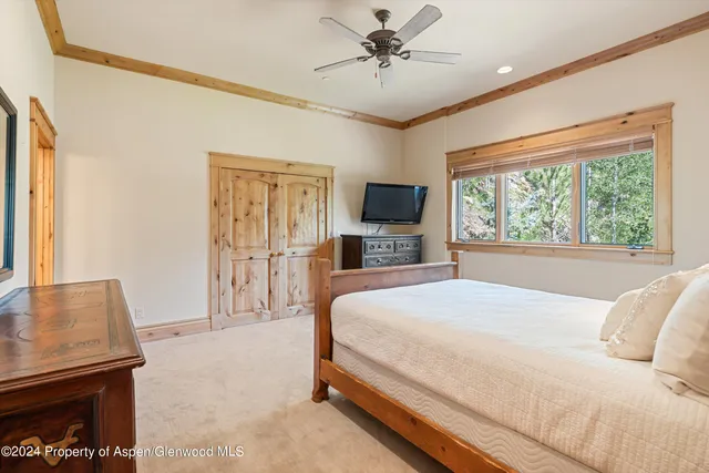 a bedroom with a large bed a flat tv screen and dresser