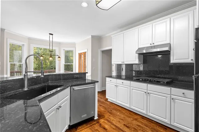 a kitchen with granite countertop a sink and white cabinets