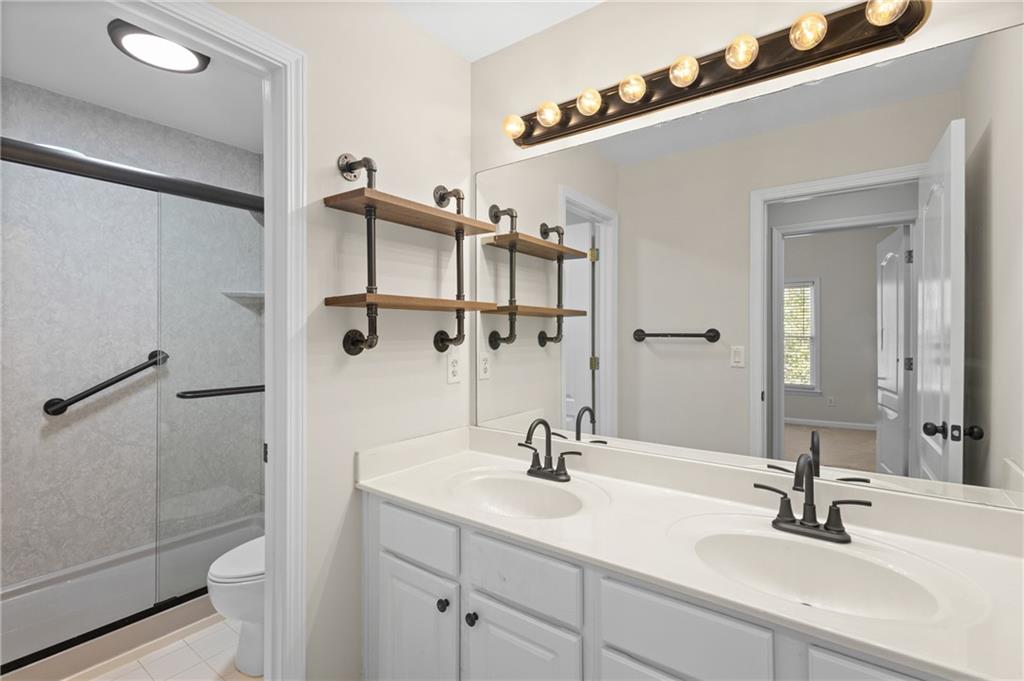 3685 Rolling Creek Drive Northeast Buford, GA 30519 - Photo 26 of 48 a bathroom with a double vanity sink a toilet and a mirror