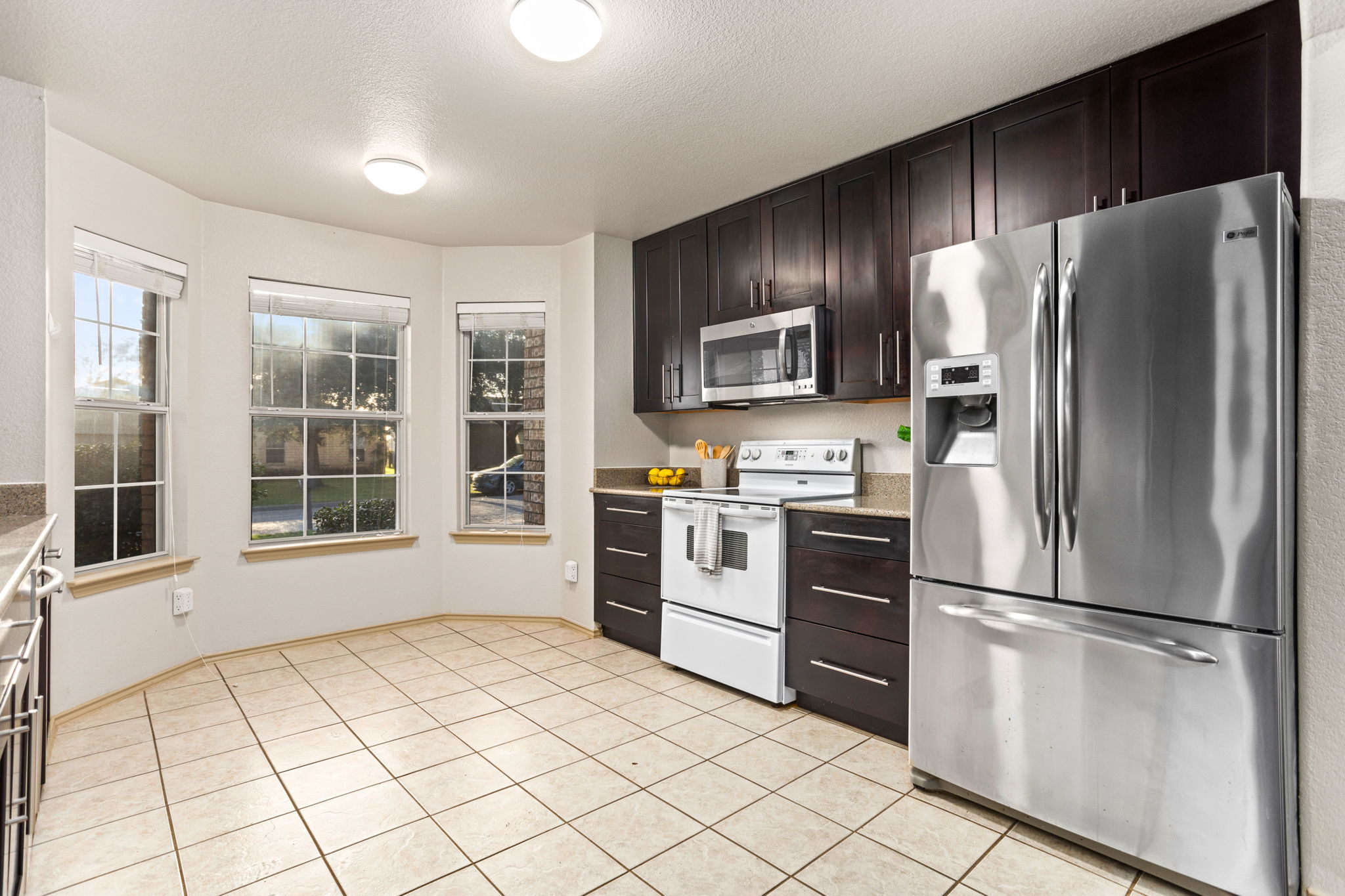 409 Lydia Lane Thrall, TX 76578 - Photo 10 of 25 a kitchen with granite countertop stainless steel appliances a refrigerator sink and microwave