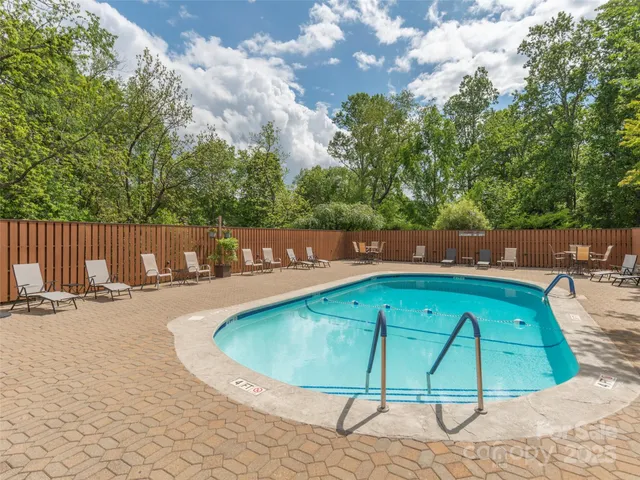 a view of a swimming pool with a patio and wooden fence