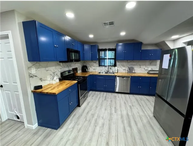 a kitchen with stainless steel appliances granite countertop wooden cabinets a stove a sink and a refrigerator