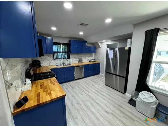 a kitchen with kitchen island a counter top space a sink stainless steel appliances and cabinets