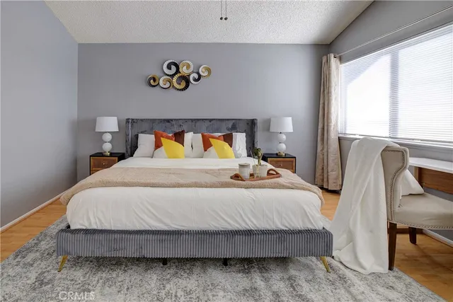 a bedroom with a bed and dresser with wooden floor