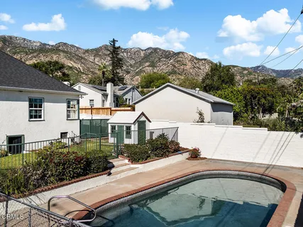 a view of a white house with a yard plants and large tree