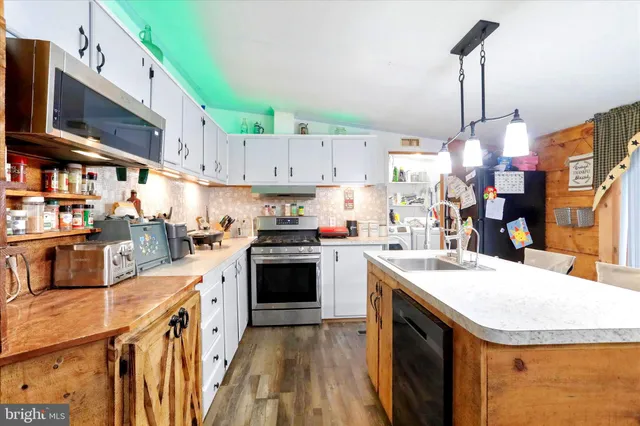 a kitchen with stainless steel appliances granite countertop a sink a stove and a wooden floors