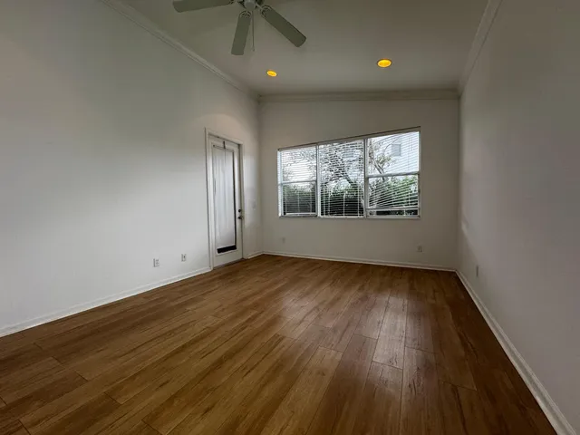 an empty room with wooden floor and windows