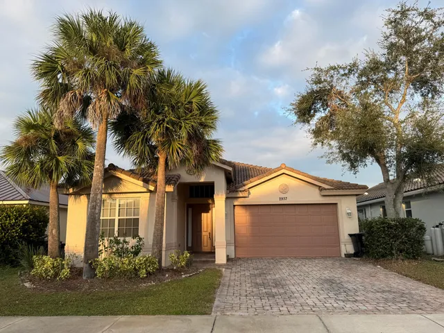 front view of house with a yard and palm trees