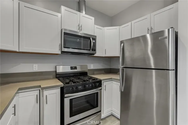 a kitchen with stainless steel appliances white cabinets white stove a microwave and a refrigerator
