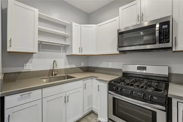a kitchen with stainless steel appliances granite countertop grey cabinets a stove a sink and dishwasher