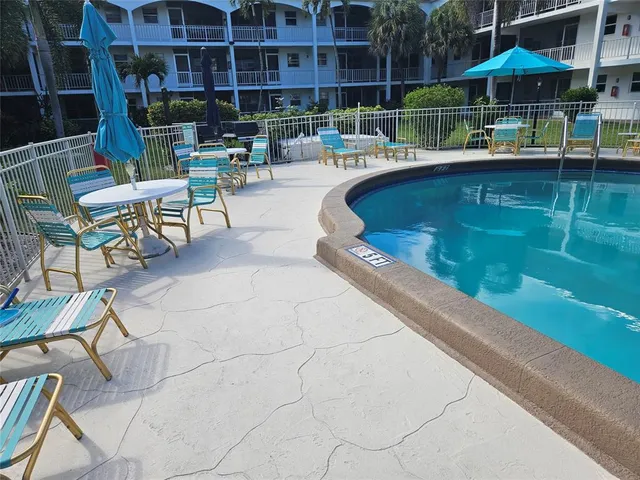 a view of swimming pool with outdoor seating and house in the background
