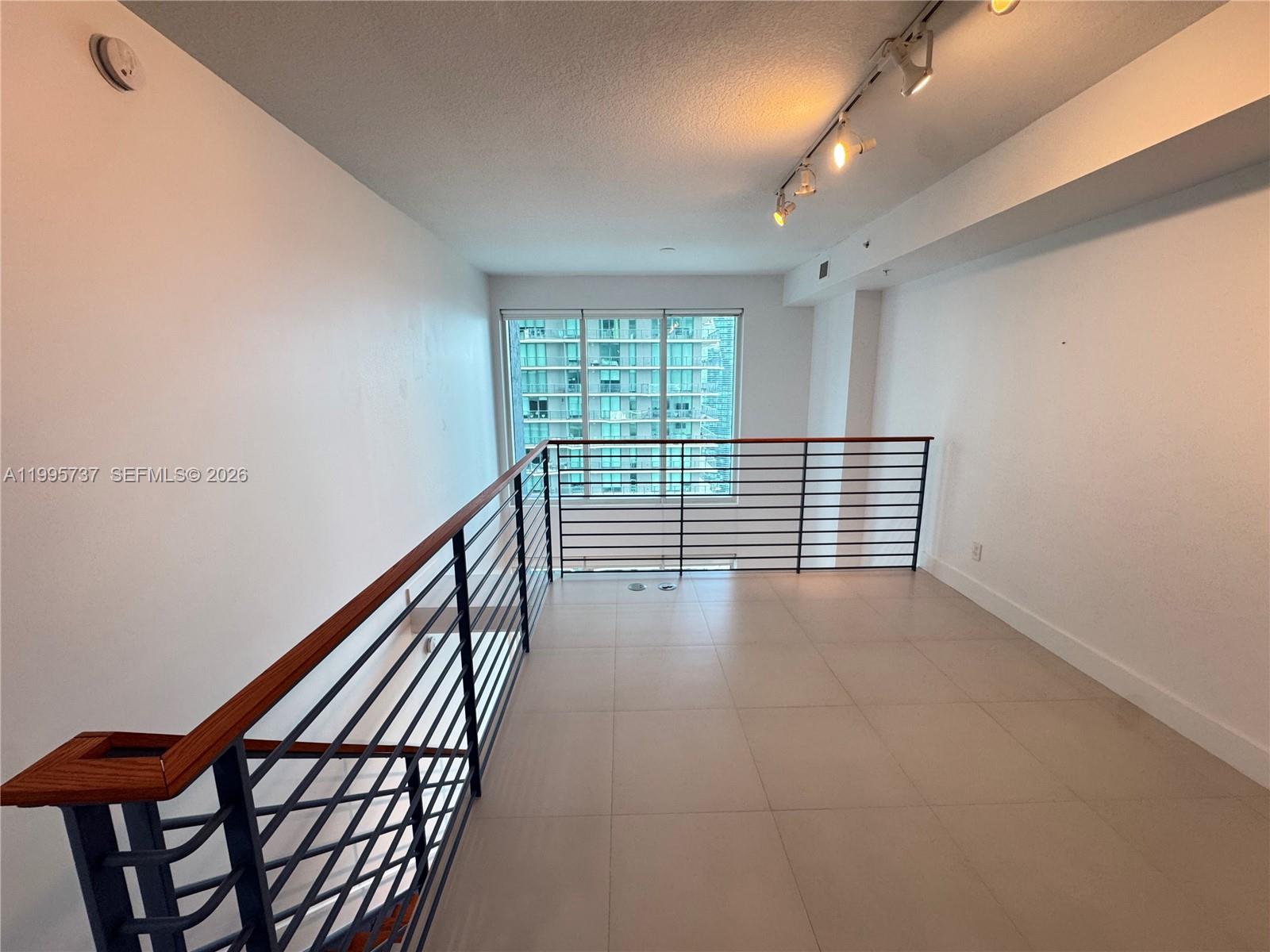 60 Southwest 13th Street, Unit 2606 Miami, FL 33130 - Photo 12 of 15 a view of an empty room with wooden floor and windows
