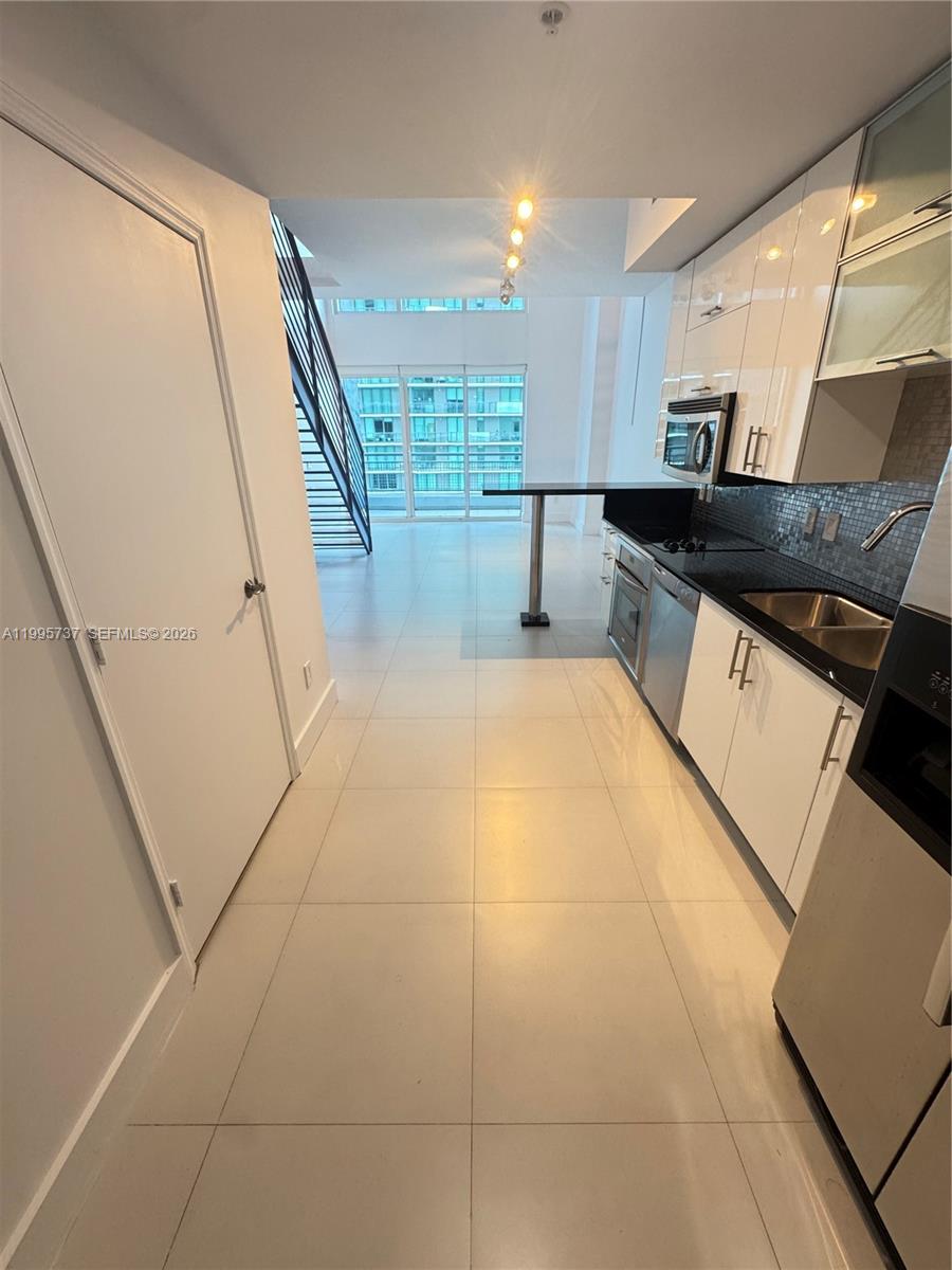 60 Southwest 13th Street, Unit 2606 Miami, FL 33130 - Photo 3 of 15 a large white kitchen with stainless steel appliances granite countertop a sink and cabinets
