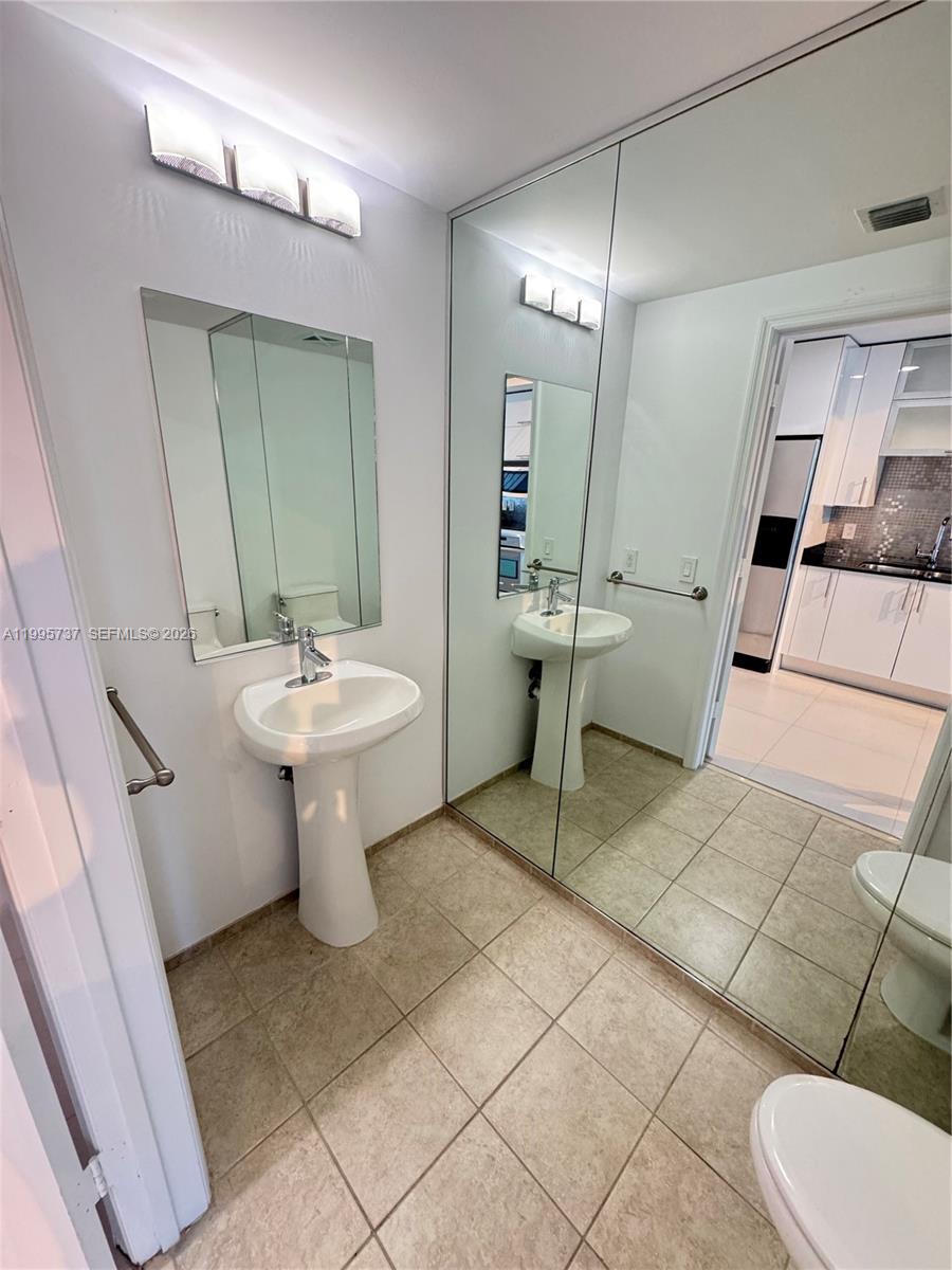 60 Southwest 13th Street, Unit 2606 Miami, FL 33130 - Photo 9 of 15 a bathroom with a sink toilet and mirror
