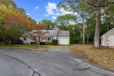 a view of a house with a yard and large trees
