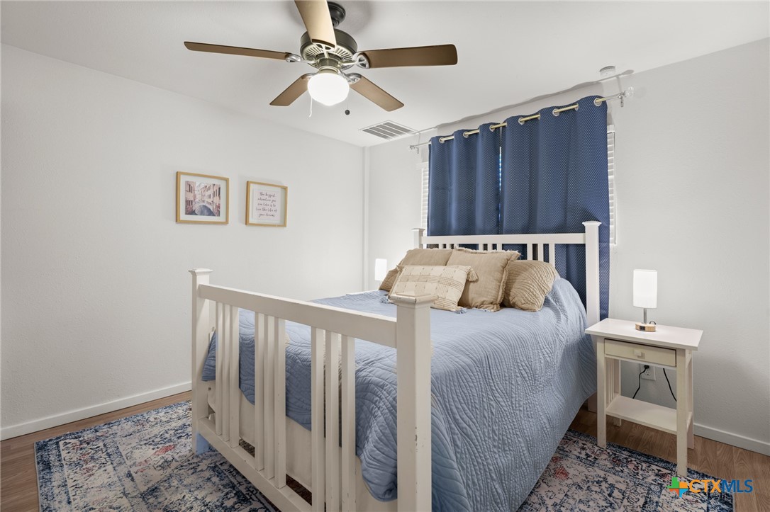 9725 Bock Road Buda, TX 78610 - Photo 34 of 37 An inviting bedroom features warm wood flooring and a refreshing ceiling fan.