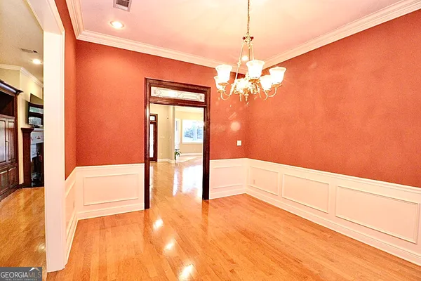 a view of a hallway with wooden floor and chandelier