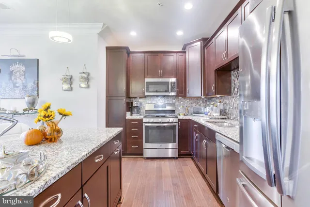 a kitchen with stainless steel appliances granite countertop wooden cabinets a stove a sink and a refrigerator