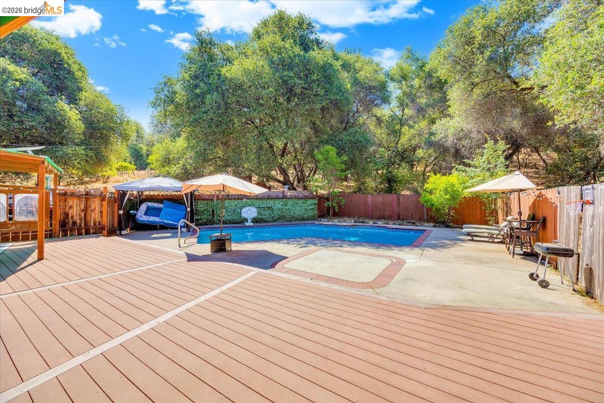 8733 Fraguero Road Sonora, CA 95370 - Photo 61 of 73 Spacious outdoor area featuring a built-in swimming pool, a large wood-look deck, a concrete patio, and a wood privacy fence
