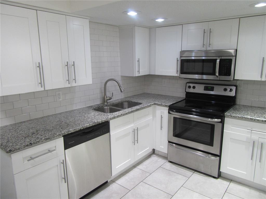 11913 104th Street Largo, FL 33773 - Photo 11 of 34 a kitchen with granite countertop white cabinets stainless steel appliances and sink