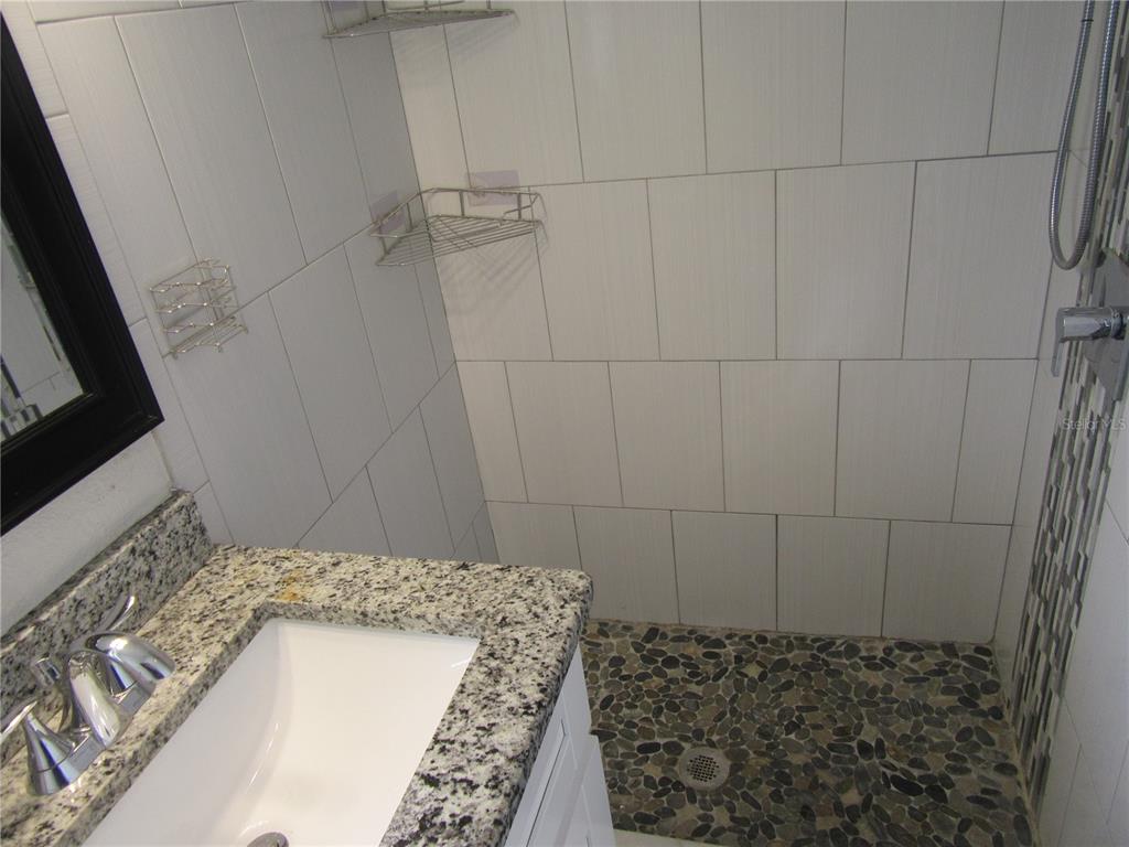 11913 104th Street Largo, FL 33773 - Photo 19 of 34 a bathroom with a granite countertop shower and a sink