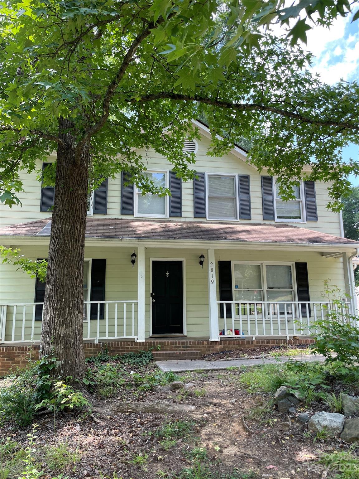 a view of a yard in front of a house with large trees