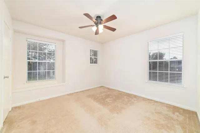 an empty room with ceiling fan and windows
