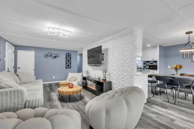 a living room with furniture kitchen view and a flat screen tv