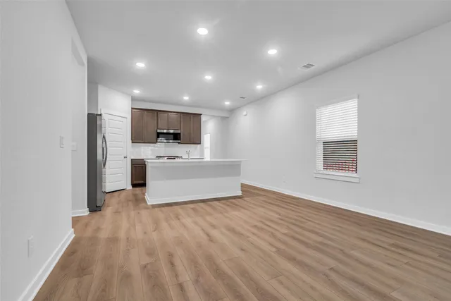 a view of a electric appliances in kitchen and empty room with wooden floor
