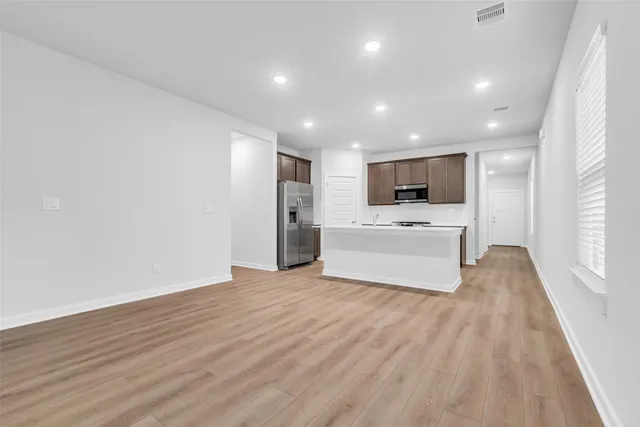 a view of a electric appliances in kitchen and empty room with wooden floor