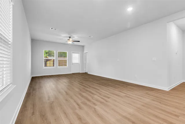 an empty room with wooden floor and windows