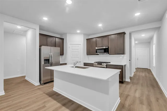 a kitchen with stainless steel appliances a stove top oven a refrigerator and a sink