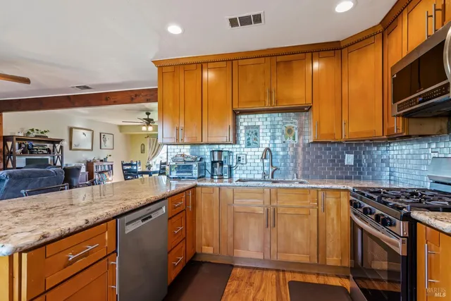 a kitchen with granite countertop wooden cabinets stainless steel appliances a sink and a counter top space