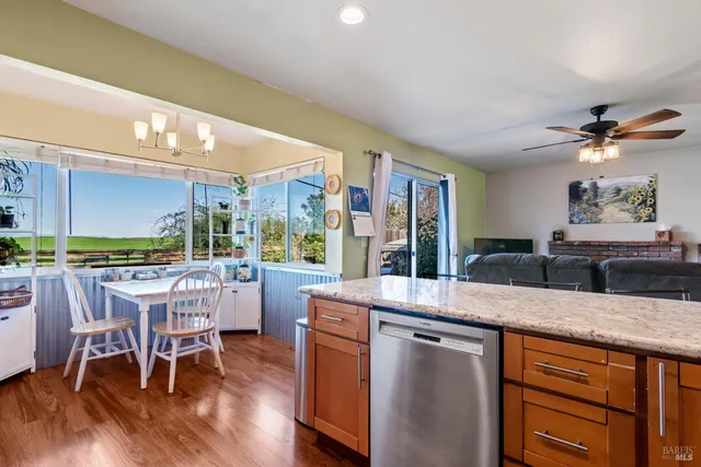 a open kitchen with stainless steel appliances granite countertop a stove a refrigerator a kitchen island a dining table and chairs