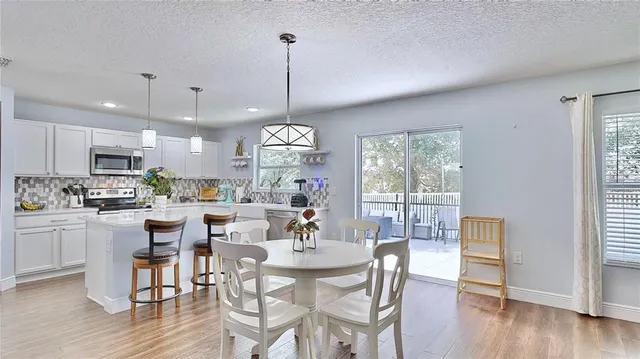 a view of a dining room and livingroom with furniture wooden floor a chandelier