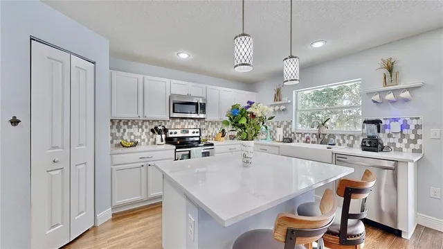 a kitchen with stainless steel appliances granite countertop a stove refrigerator a sink dishwasher a dining table and chairs with wooden floor