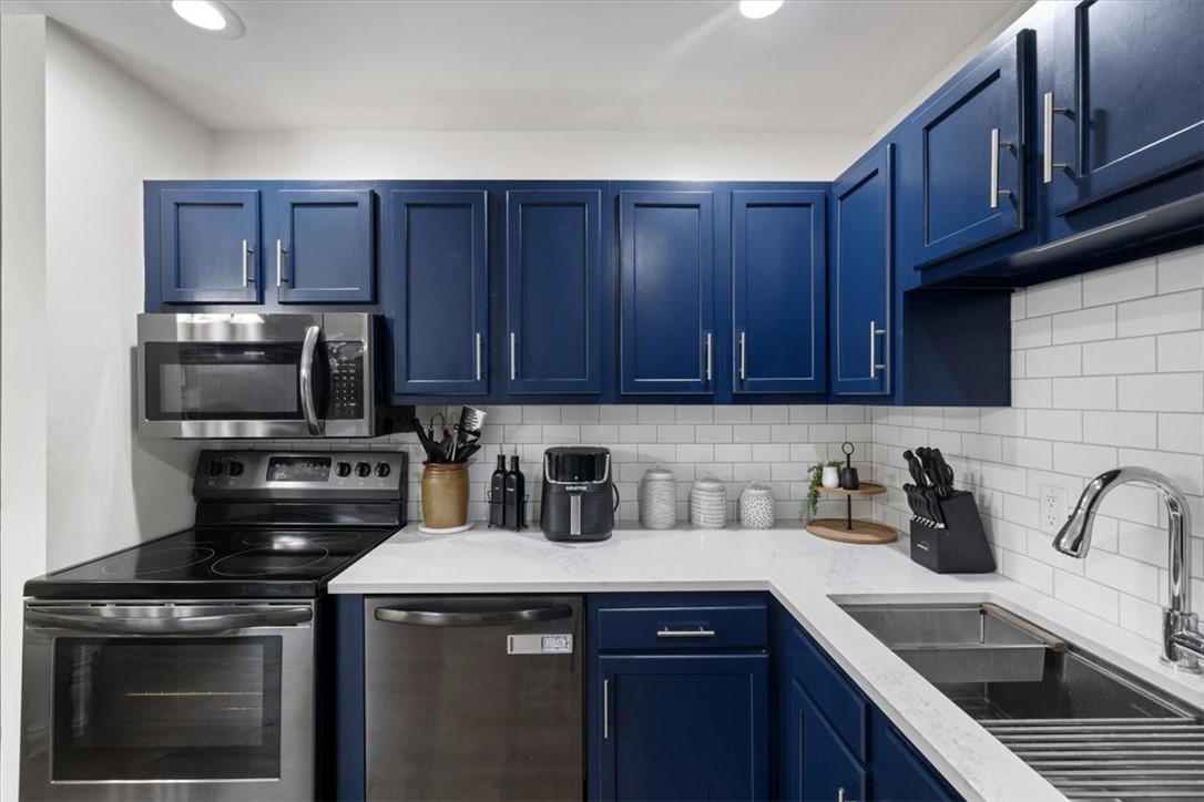 1482 Lee Road Troy, OH 45373 - Photo 20 of 30 This modern kitchen features bright blue cabinetry, white countertops, and sleek stainless steel appliances.