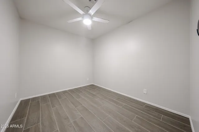 an empty room with wooden floor and fan