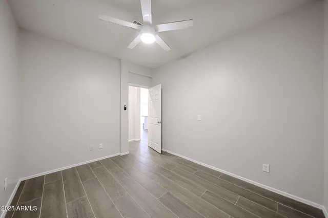 an empty room with wooden floor and fan