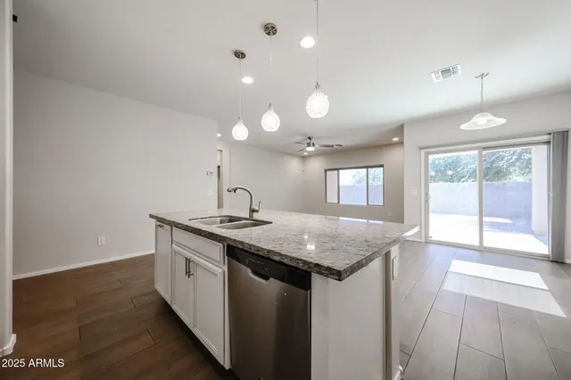 a kitchen with stainless steel appliances granite countertop a sink a stove and a wooden floors