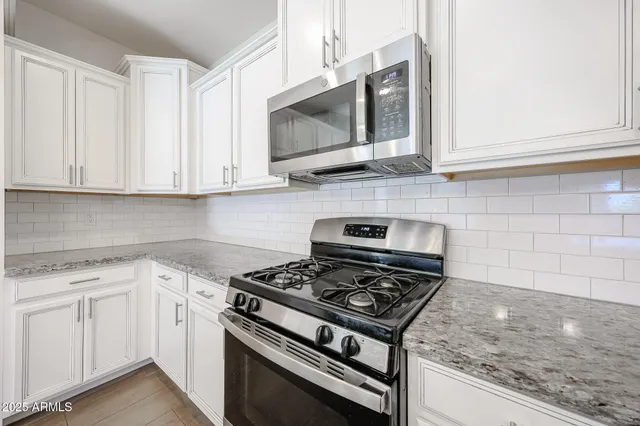 a kitchen with white cabinets and appliances