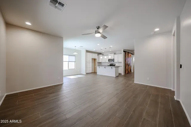 an empty room with wooden floor ceiling fan and windows