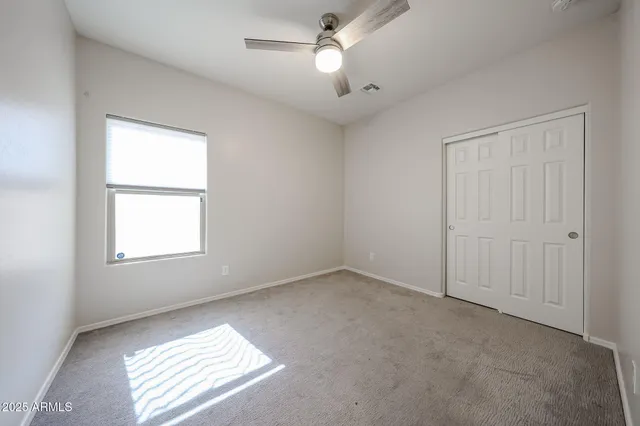 an empty room with windows and fan