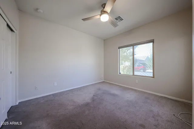 an empty room with windows and fan