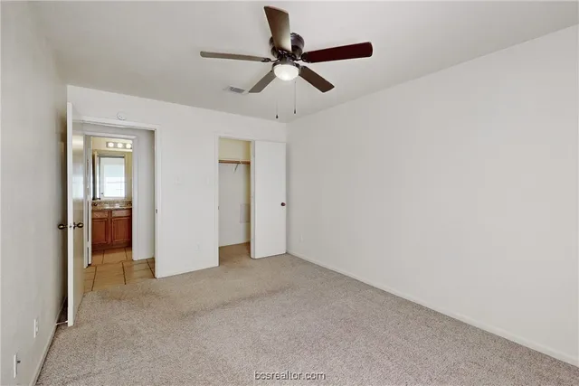 an empty room with ceiling fan and windows