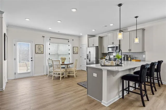 a kitchen with stainless steel appliances kitchen island granite countertop a table chairs and a refrigerator