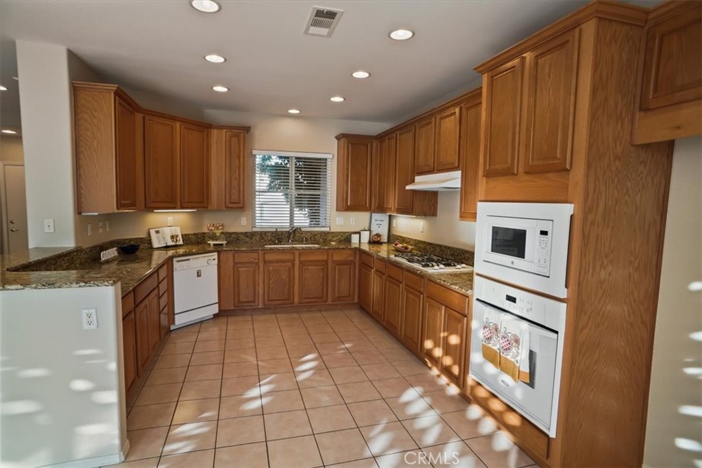 20046 Christopher Lane Saugus, CA 91350 - Photo 6 of 25 a kitchen with stainless steel appliances granite countertop a stove a sink dishwasher and a refrigerator