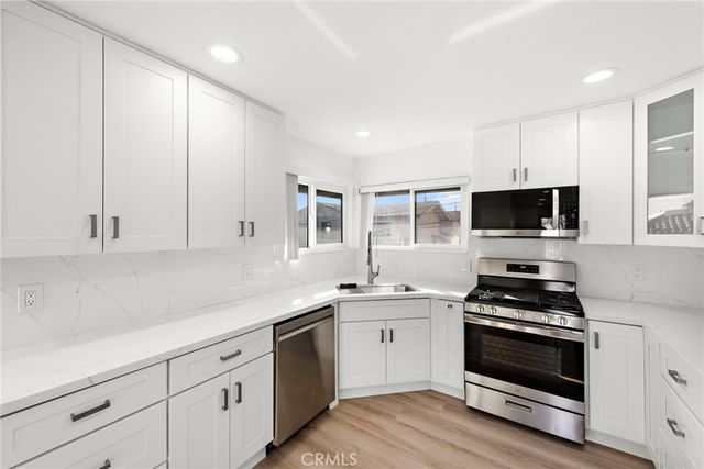 a kitchen with white cabinets stainless steel appliances and sink