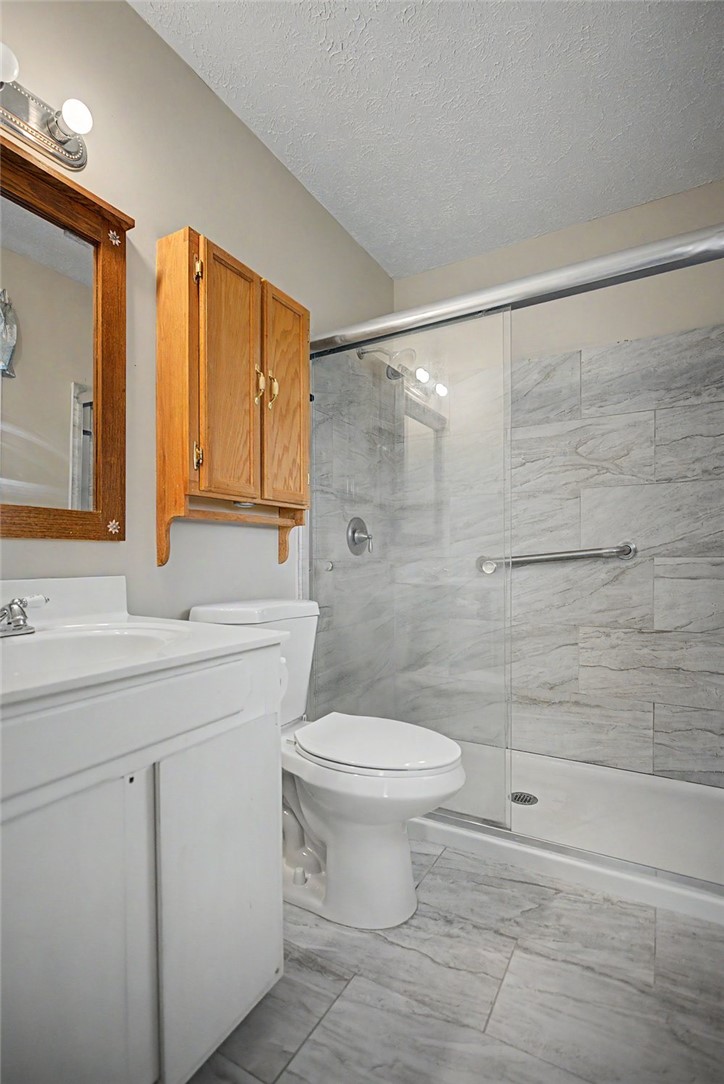 115 Brunson Drive Pickens, SC 29671 - Photo 19 of 29 A well-appointed bathroom with a tiled shower and light wood cabinetry.